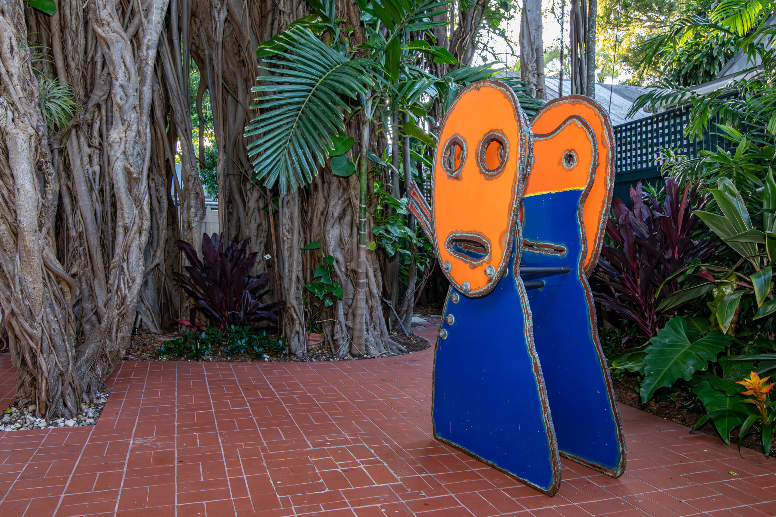 Sculpture of orange head on top of a cobalt blue base.