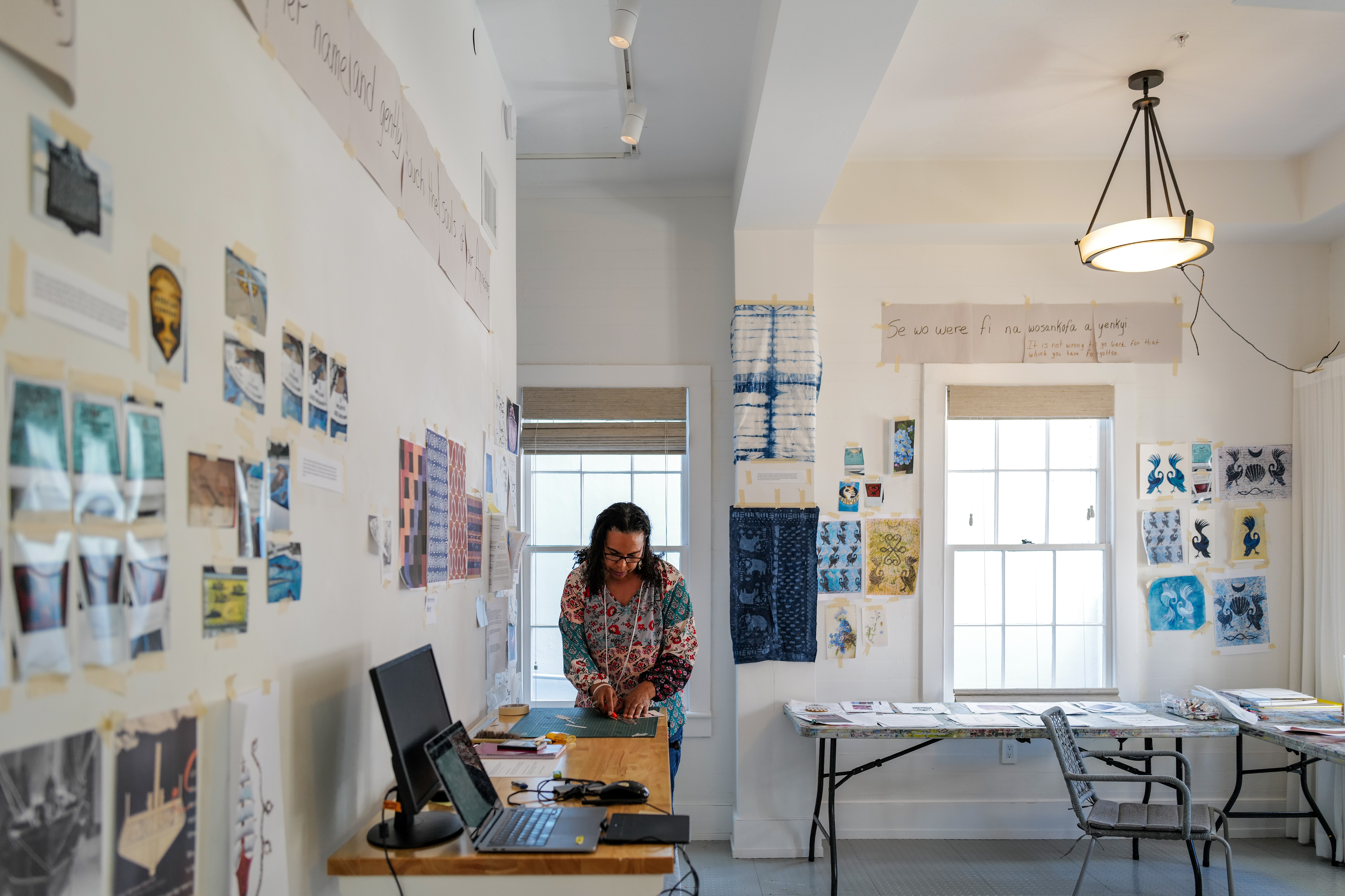 Image of the inside of the private residences with a person standing in the center of the image. The walls around the person have art and images posted on them.