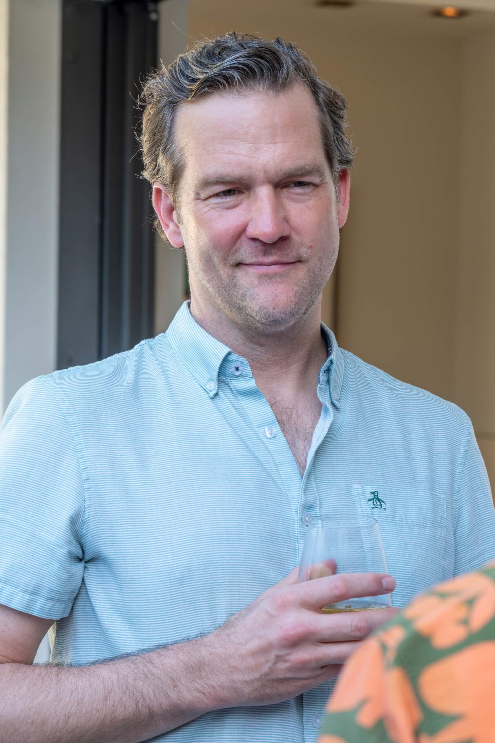 Man smiling while holding a drink at a social gathering.