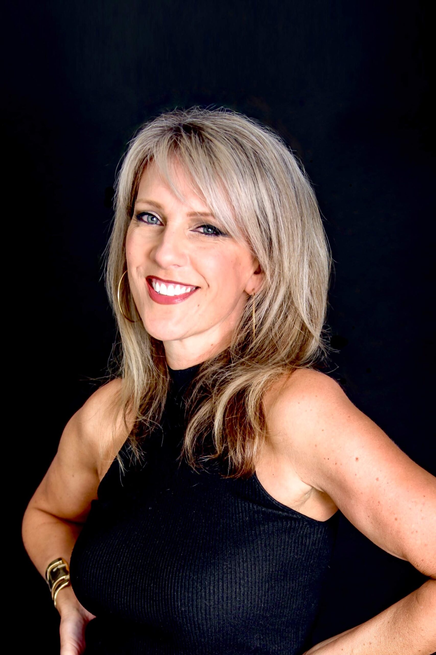 Woman smiling in a portrait against a black background.