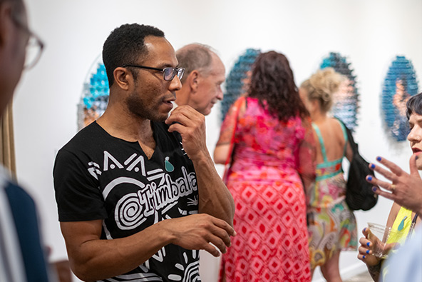 Visitors talk together while viewing contemporary artwork displayed in a gallery at The Studios of Key West.