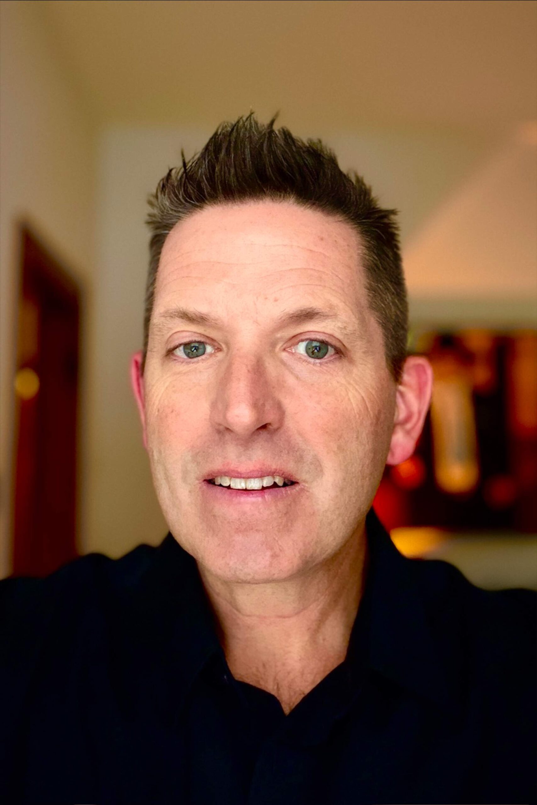 Man smiling in a close-up indoor portrait.