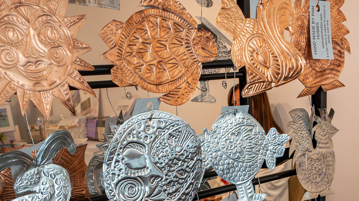 Handmade copper and silver tin ornaments featuring turtles, fish, suns, birds, and tropical designs by artist Pam Hobbs.
