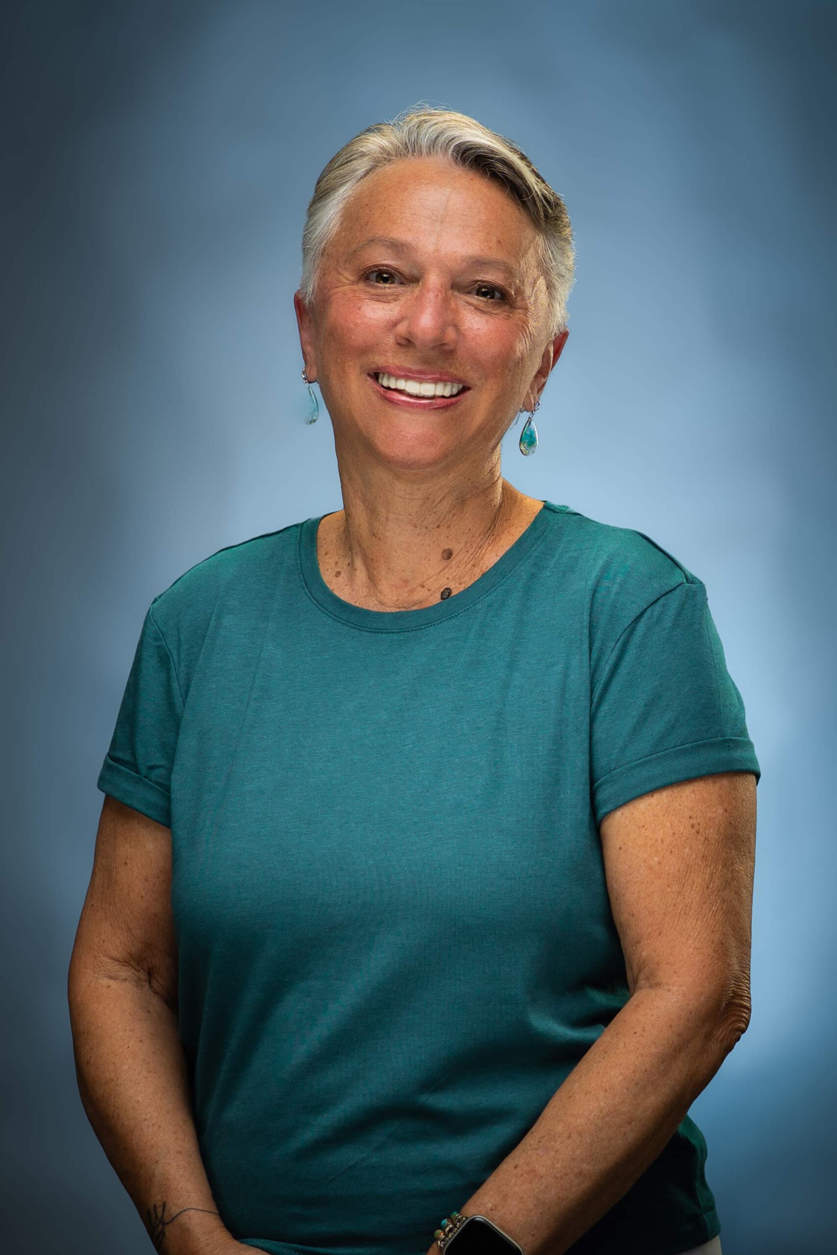 Headshot of Karen smiling in a teal top against a blue studio background.