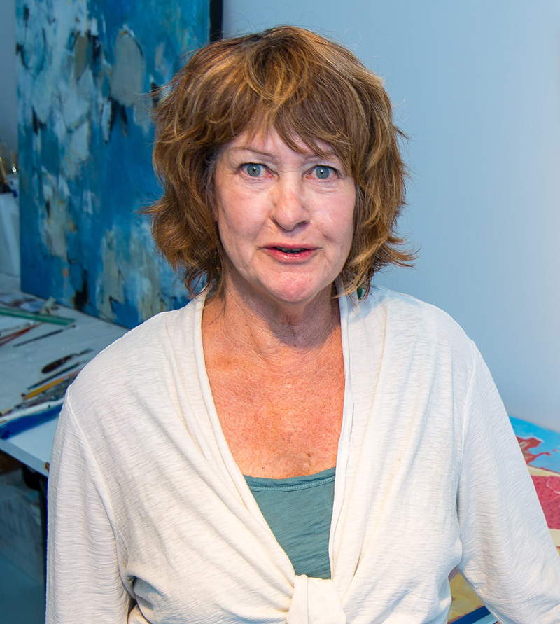 Lucy Paige in her studio, with a large blue abstract painting behind her.
