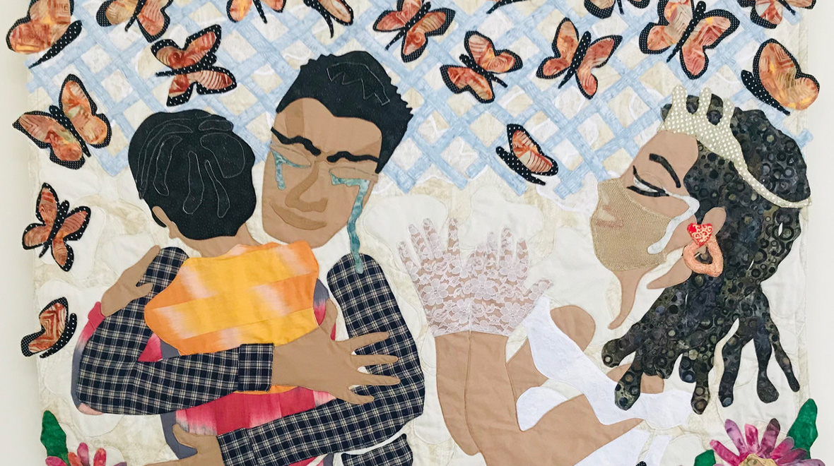 Appliquéd quilt depicting two emotional embraces surrounded by orange-and-black butterflies, flowers, and layered patterned fabrics.