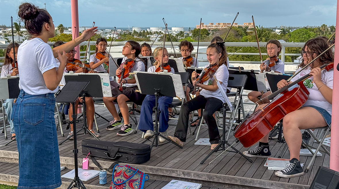 Young musicians from the Southernmost Youth Orchestra play violins and cello on Hugh’s View as their conductor leads the ensemble.