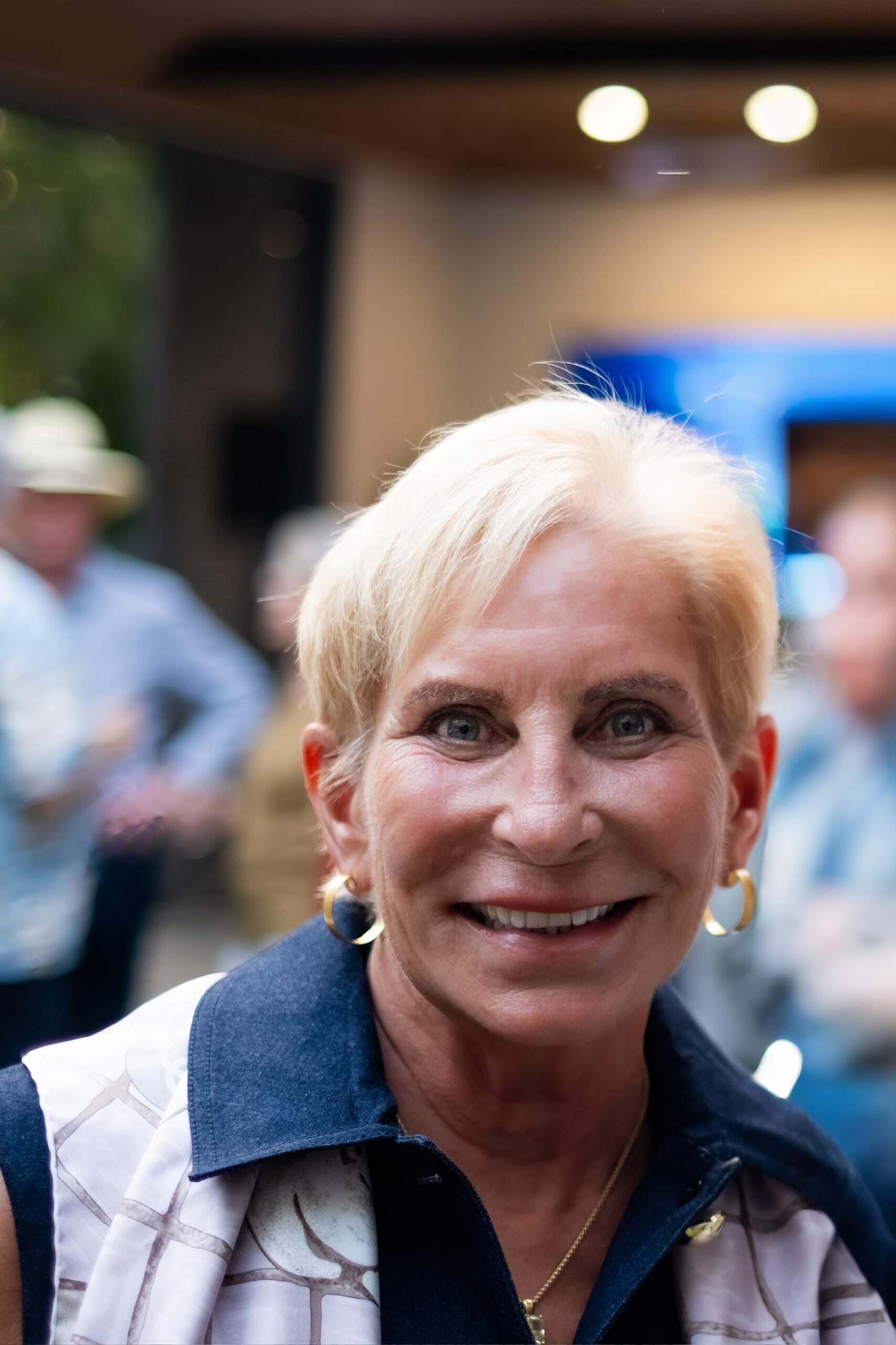 Woman with short blonde hair smiling at a social gathering.