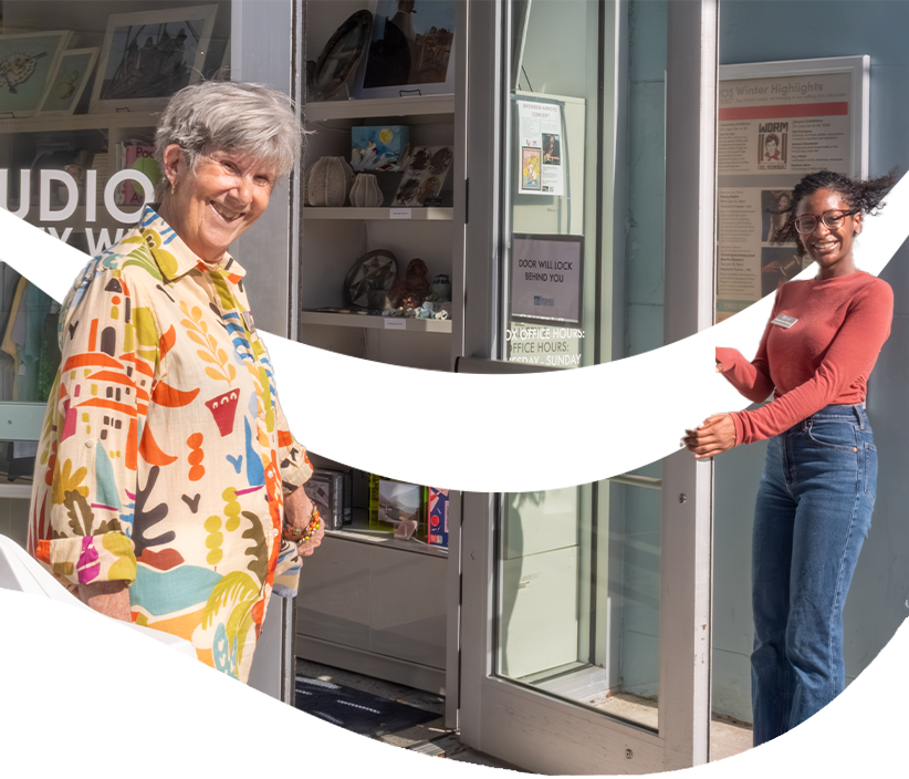 A volunteer and Studios staff member smile while welcoming visitors at the entrance to The Studios of Key West.