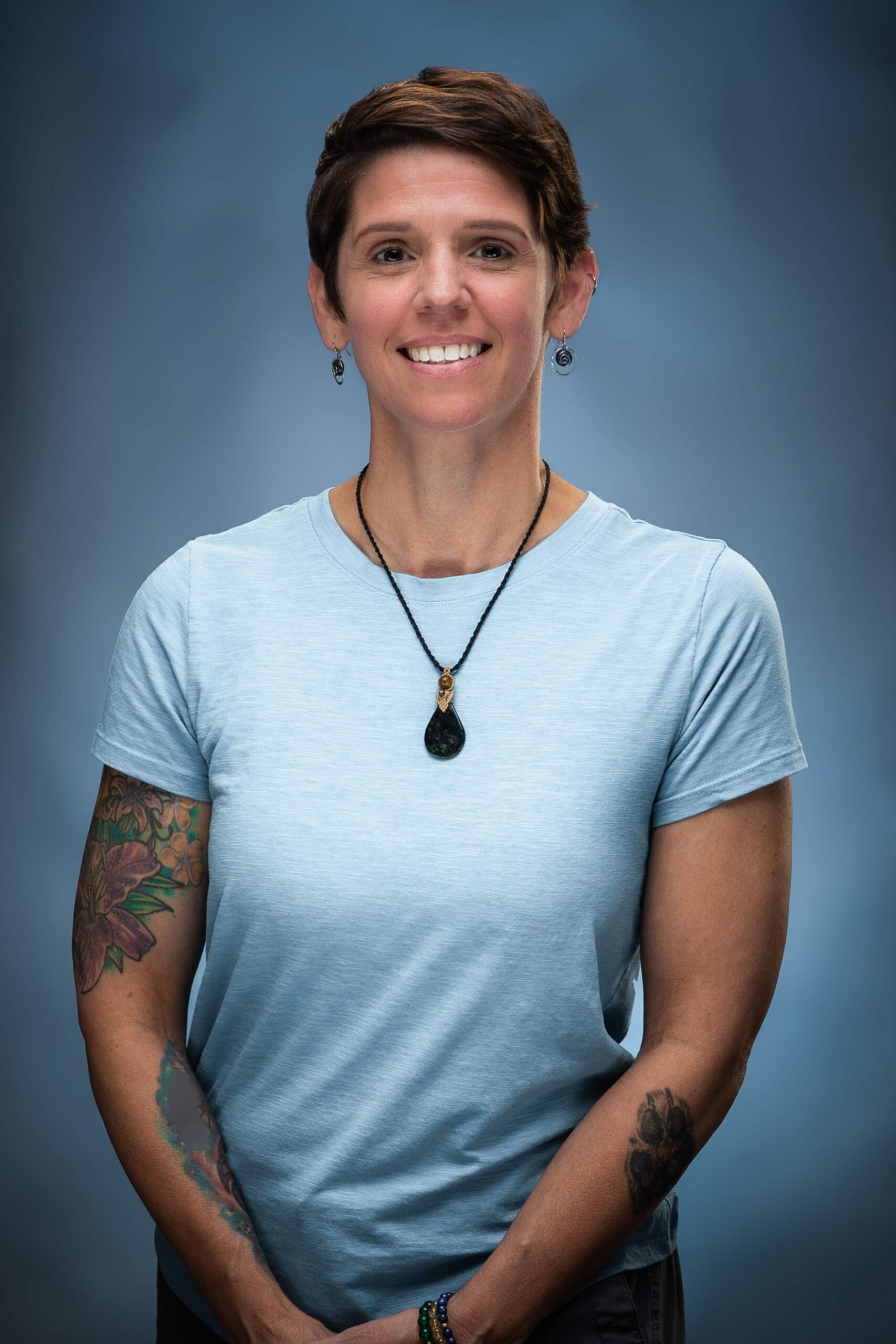 Headshot of Wendy smiling in a light blue top against a blue studio background.