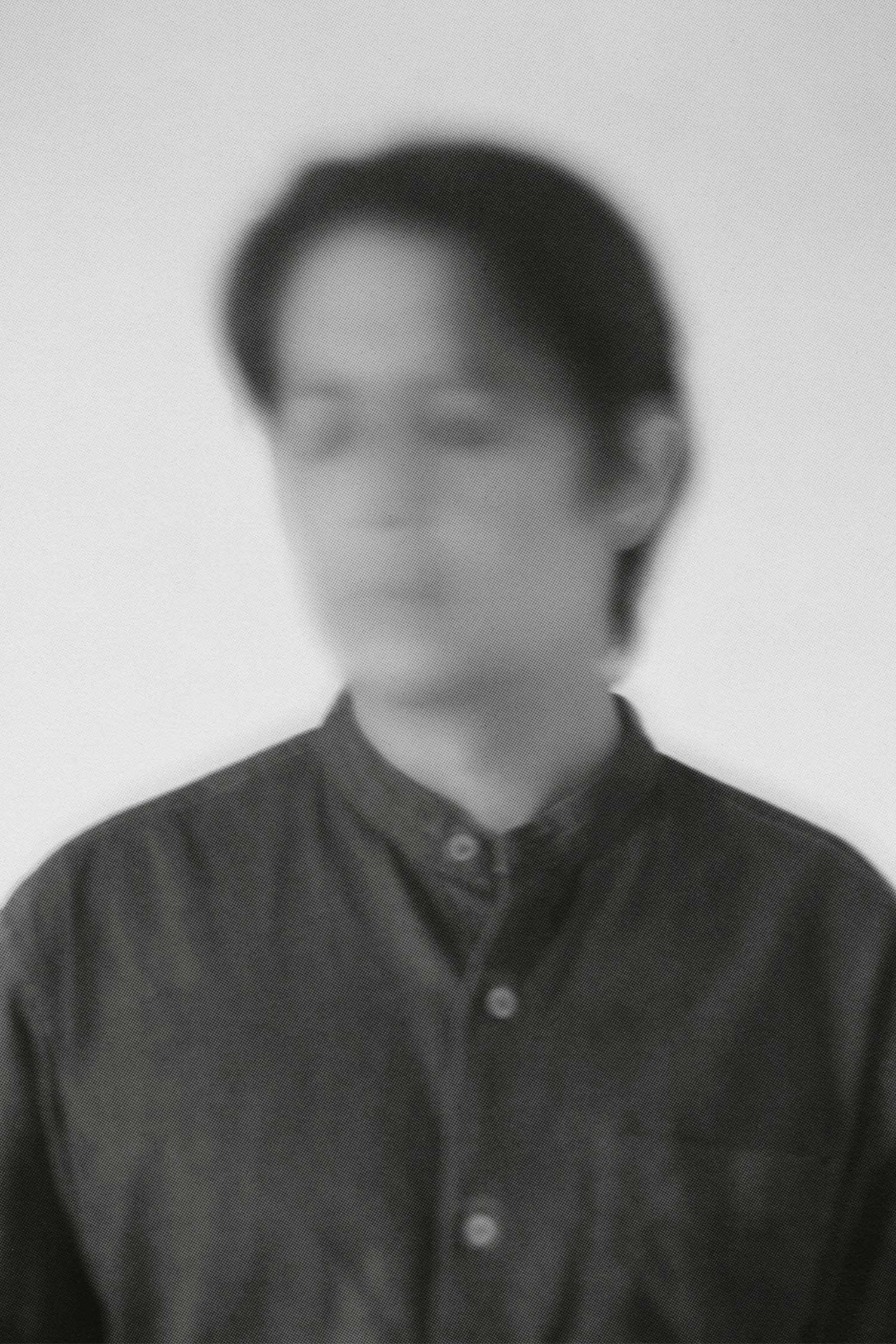 Black-and-white artist portrait of photographer Patrick Jaimes, shown in profile wearing glasses and a dark button-up shirt.
